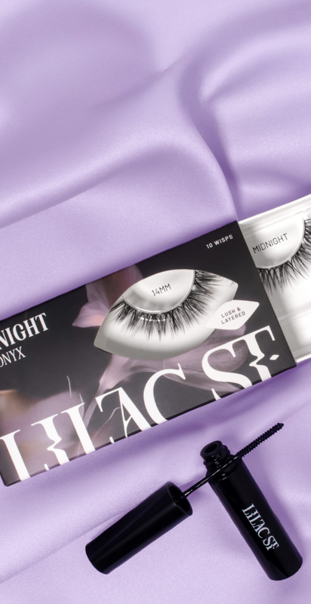 Eyelash packaging with a brush on a purple fabric background.